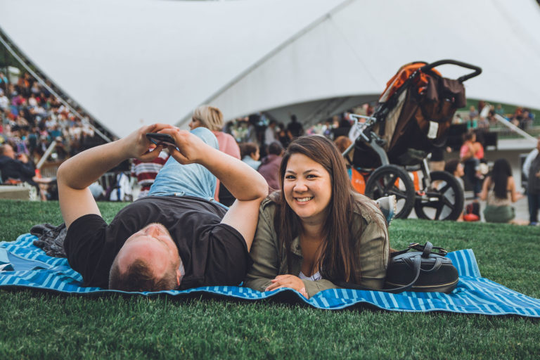 couple lying on picnic blanket in the grass.