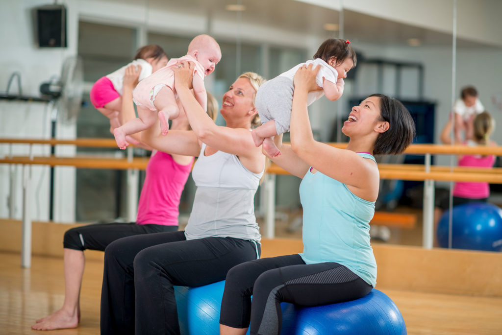 three women holding three babies in the gym